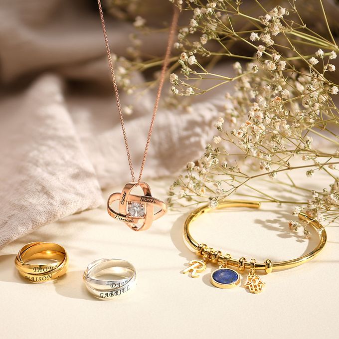 A rose gold neckalce, Gold bracelet and silver and gold rings on a light background