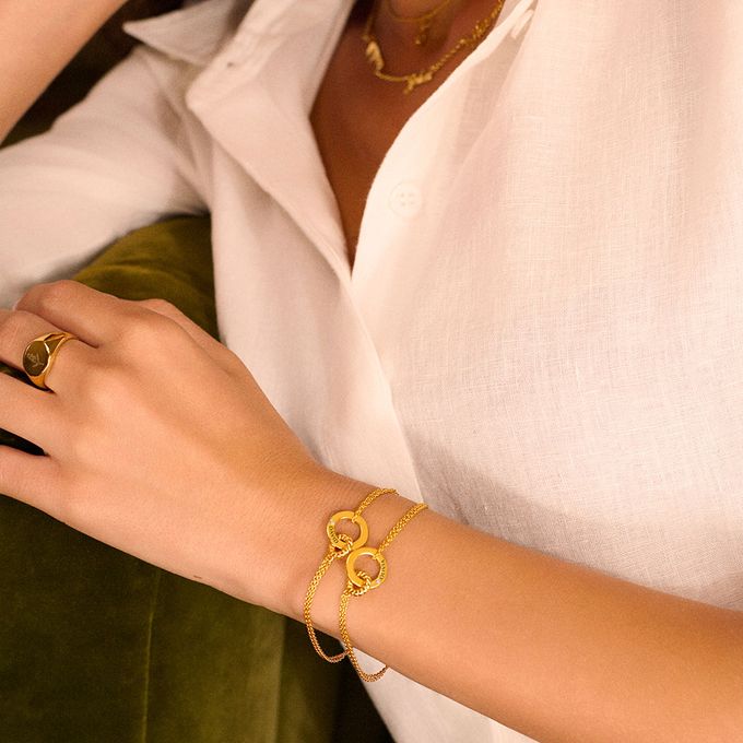 a woman wearing a gold bracelet with interlocking circle with a name engraving and diamond