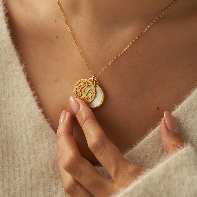 a woman wearing a gold necklace with a monogrammed initial