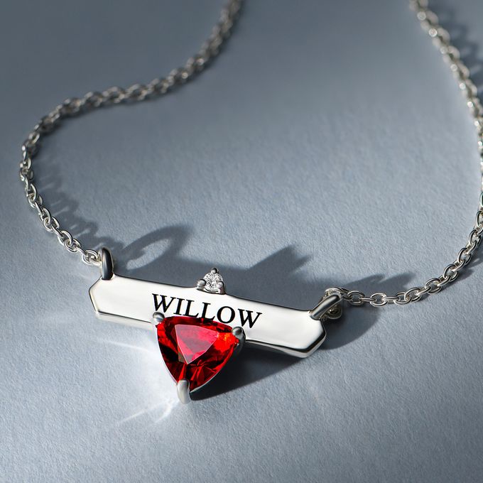 A silver necklace with the name Willow engraved a red birthstone