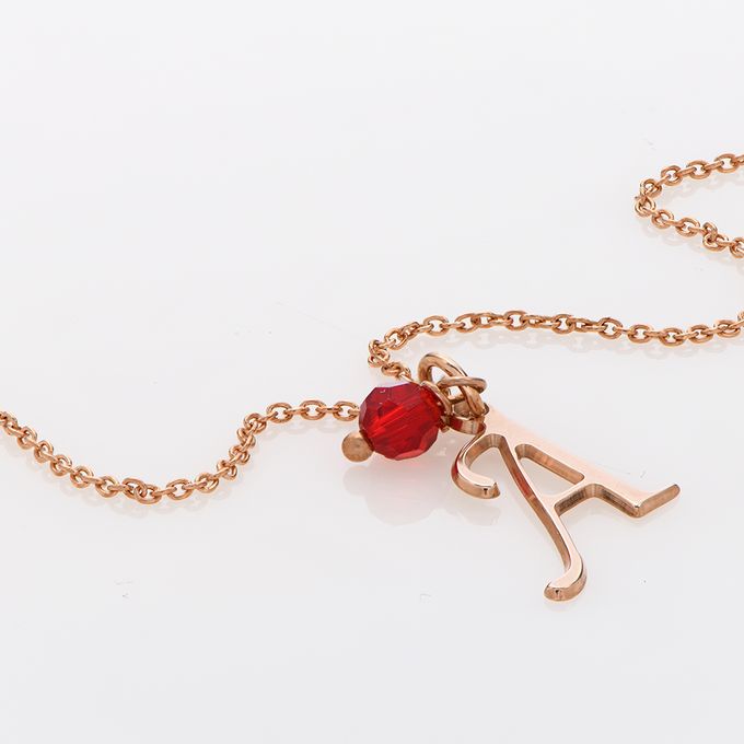 a gold necklace with a red bead hanging from it