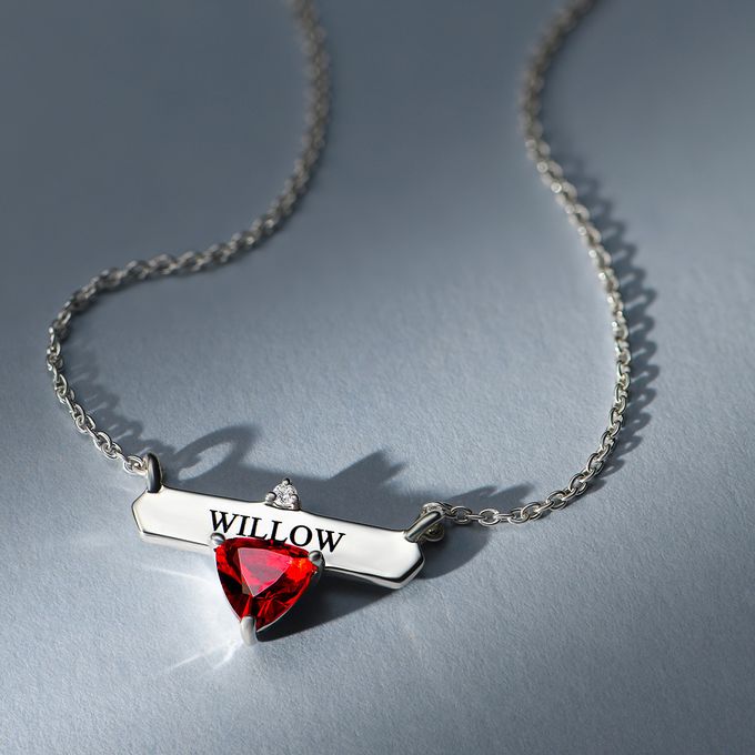 a necklace with a red stone heart and a name tag