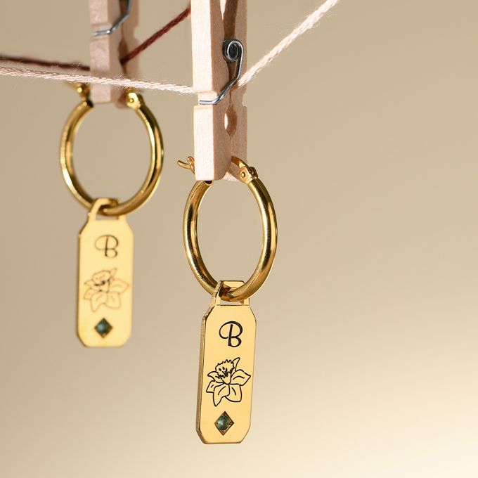 a couple of gold earrings hanging from a clothes line