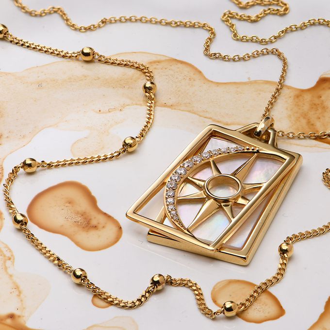 a gold necklace with a diamond and an eye on it