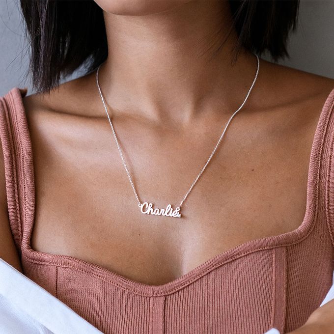 a woman wearing a necklace with the word charlotte on it
