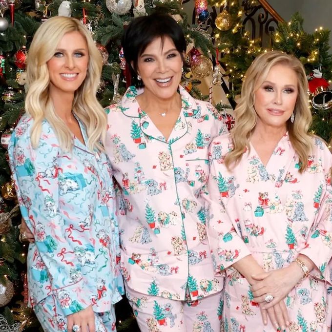 three women in matching pajamas standing in front of a christmas tree