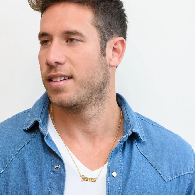 a man wearing a blue shirt and a gold necklace