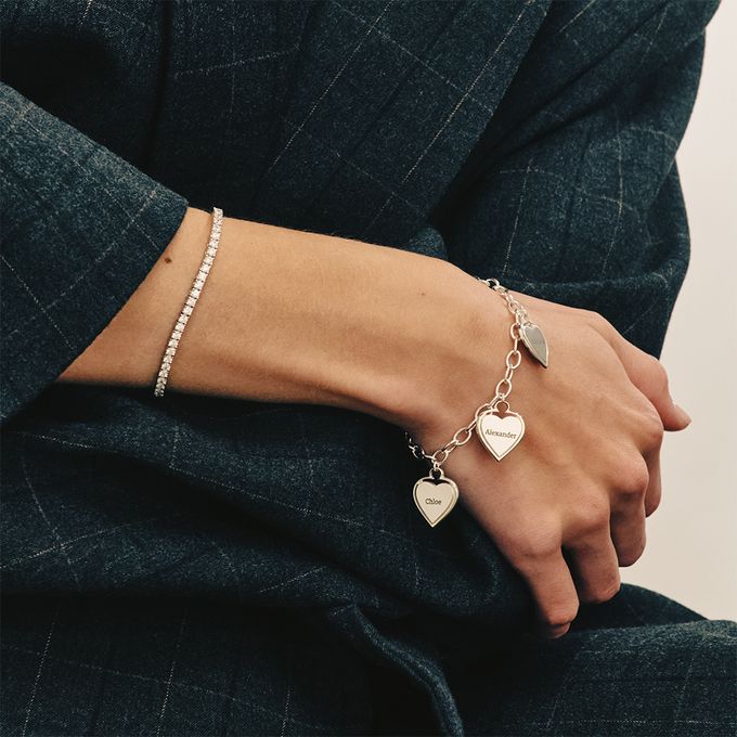 a woman wearing a bracelet with two hearts on it