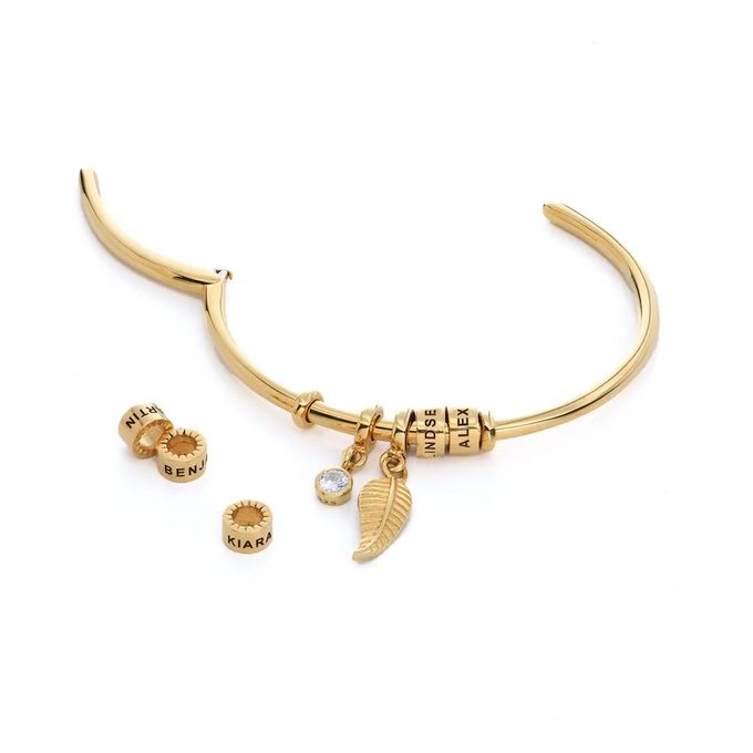 Stock image of an open  gold plated bracelet with gold and diamond charms