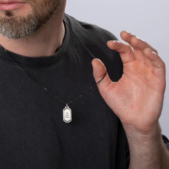 a man wearing a black t - shirt holds his hand up to his chest