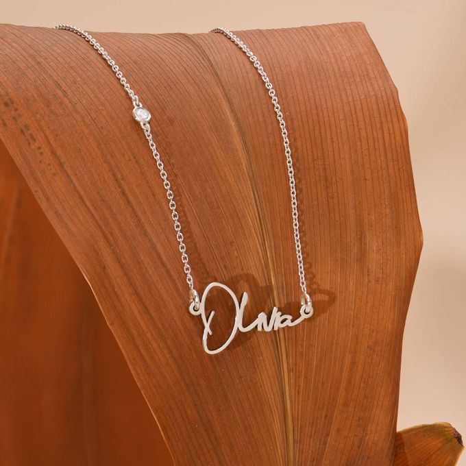 Olivia Name Necklace Paris style with Diamond in Sterling Silver a personalized necklace with the name Olivia on a wooden chair