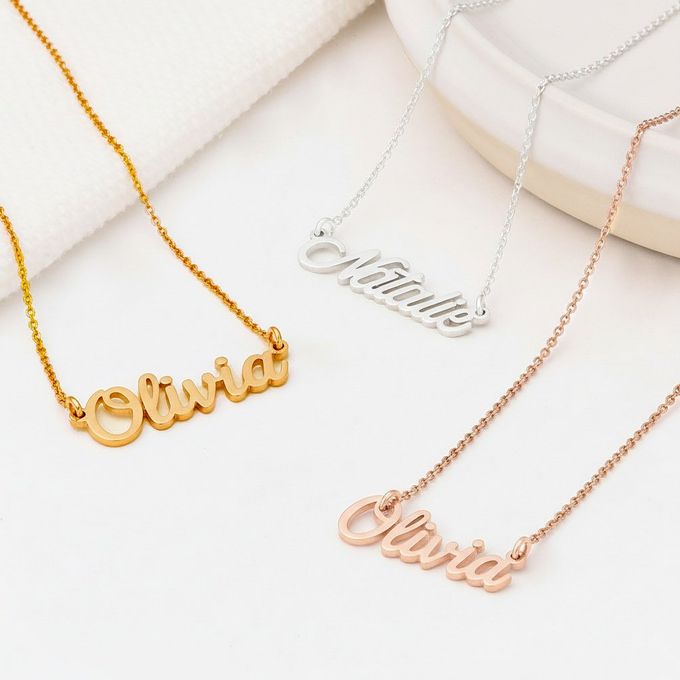 three personalized Olivia name necklaces on a white surface