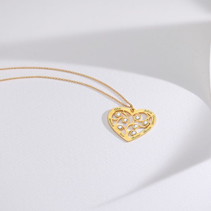a heart shaped yellow gold necklace with a diamond accent on a white surface