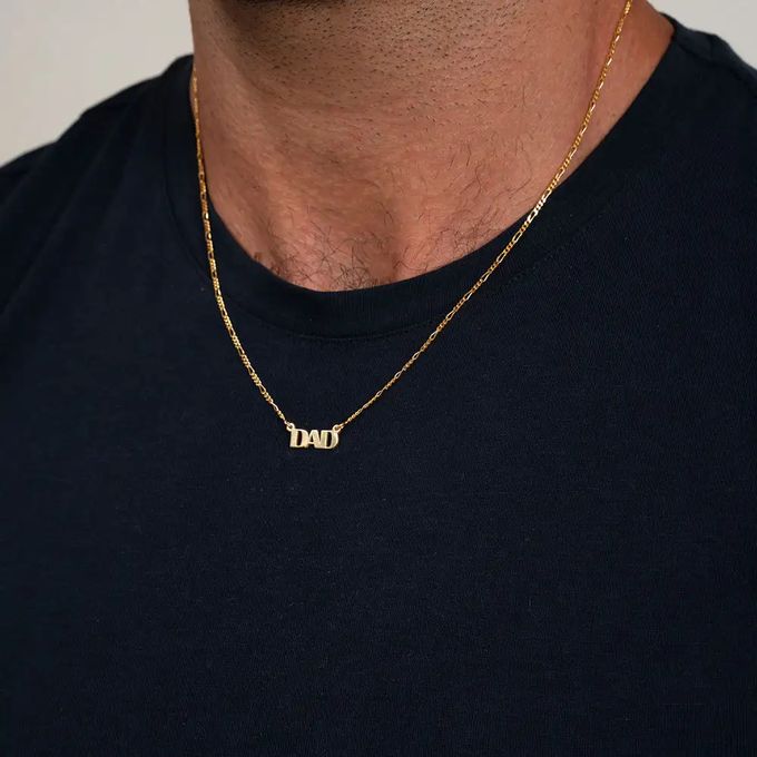 A gold name necklace that reads "Dad" in capital letters around a man's neck