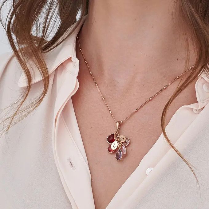 a close up of a woman wearing a five birthstone necklace