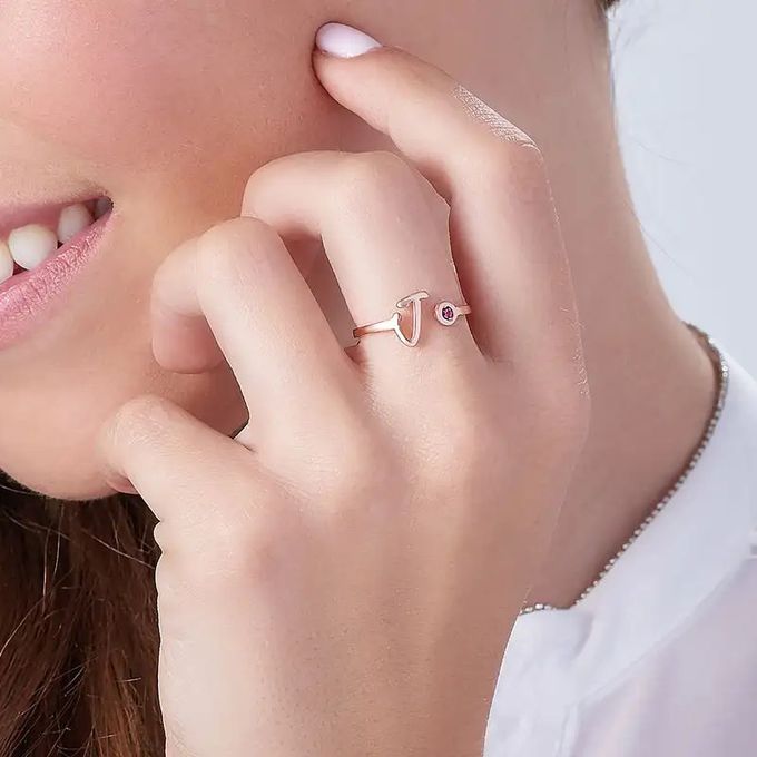 Open initial ring in rose gold with the initial J and a birthstone on a woman's finger