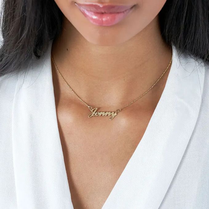 A gold name necklace that reads "Jenny" around a girl's neck
