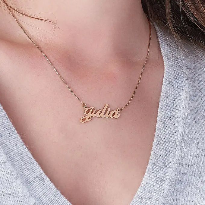 Rose gold name necklace that reads "Julia" around a woman's neck