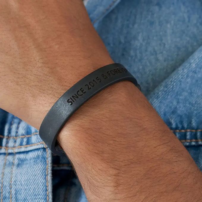 Close-up of a man's wrist with an inscribed simple black leather bracelet