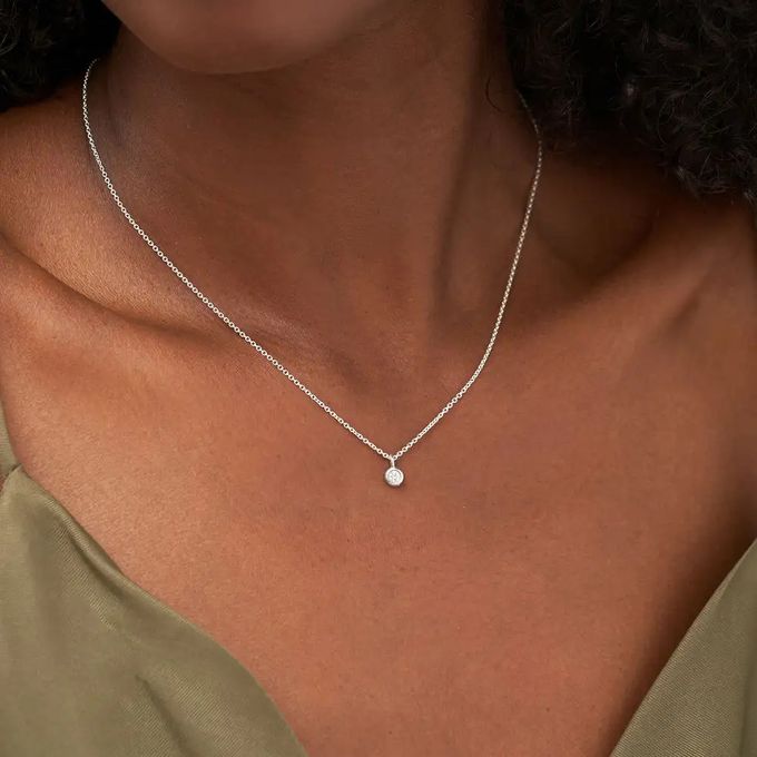 A sterling silver necklace with a diamond around a woman's neck