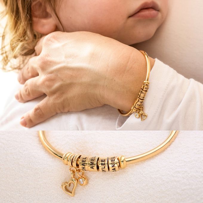 a woman wearing a gold bracelet with a heart charm