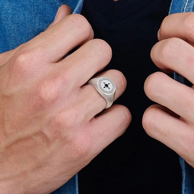 Close up of a man's hands while wearing a compass signet ring in silver