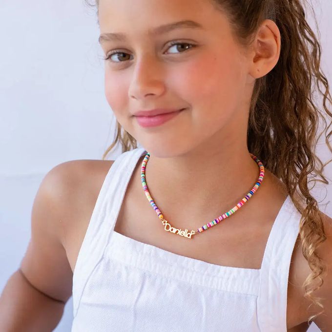 A young girl wearing a colorful bead necklace with a name pendant that reads "Danielle"