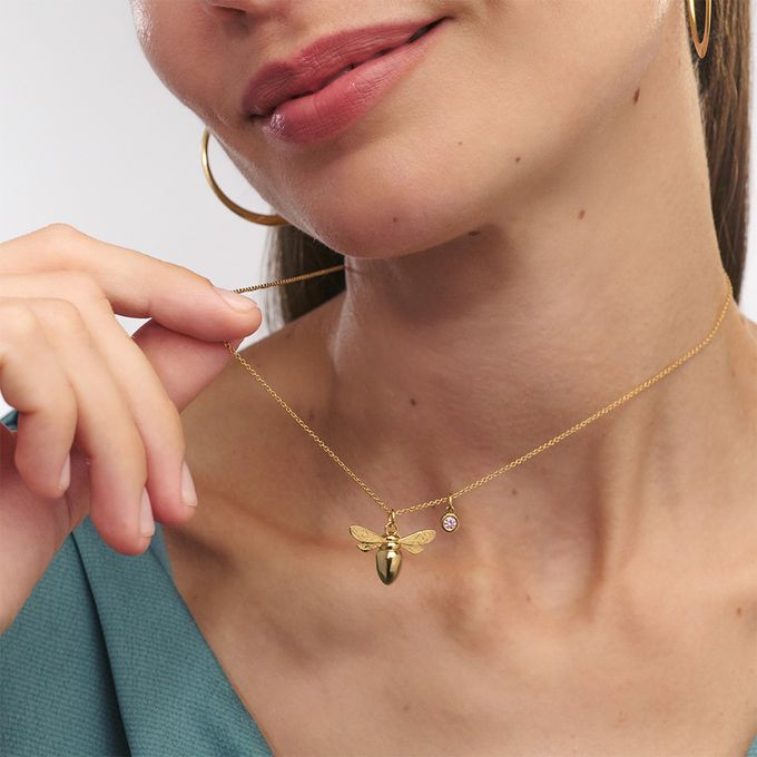 a woman wearing a necklace with a bee on it