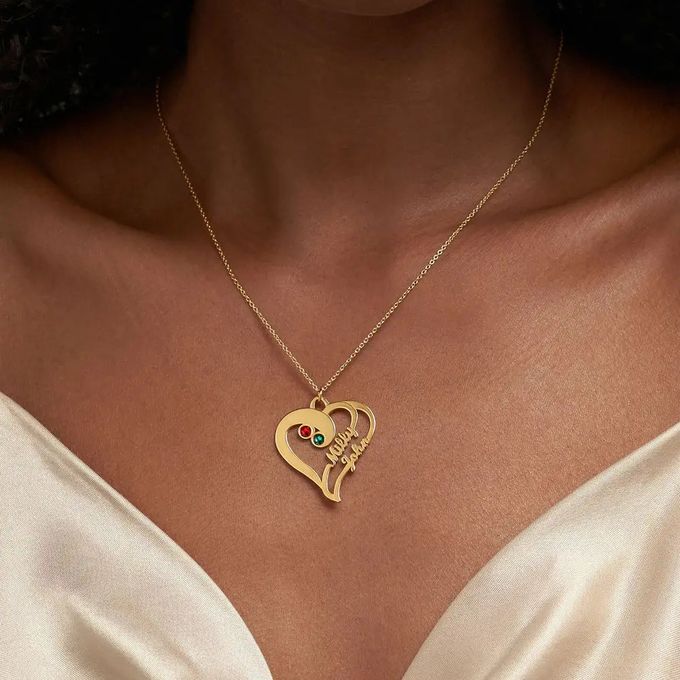 a woman wearing a gold necklace with a heart shaped pendant and birthstones