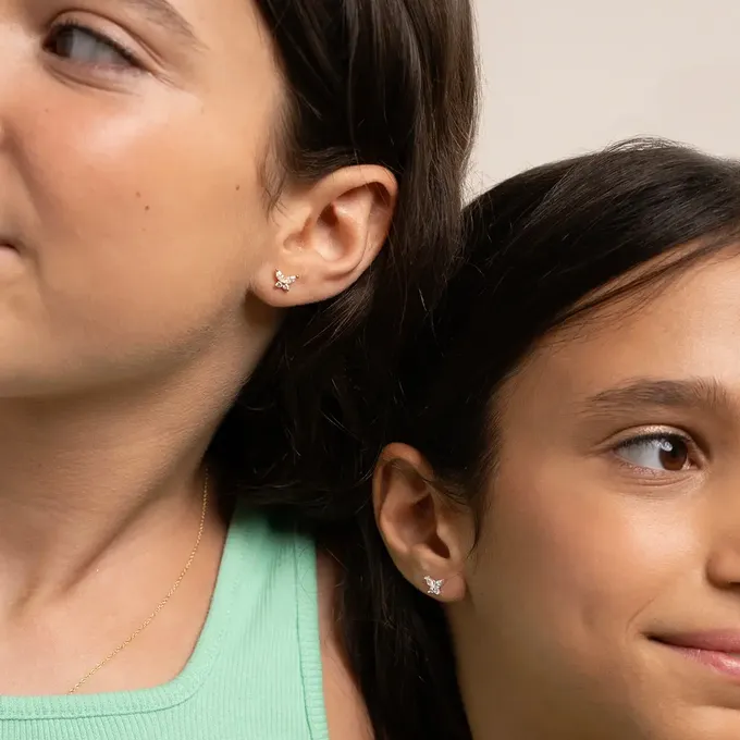 two girls with dark hair next to each other showing off their earrings