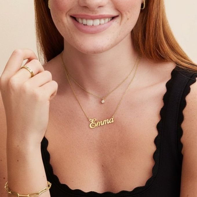 Emma Hollywood Small Name Necklace a woman in a black top is smiling wearing Necklace with the name Emma