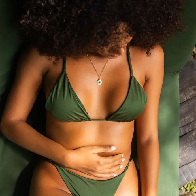 Little Ray of Sunshine Charm Necklace a woman in a green bikini with green clover necklace