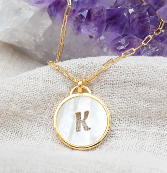 a gold necklace with a letter k on it