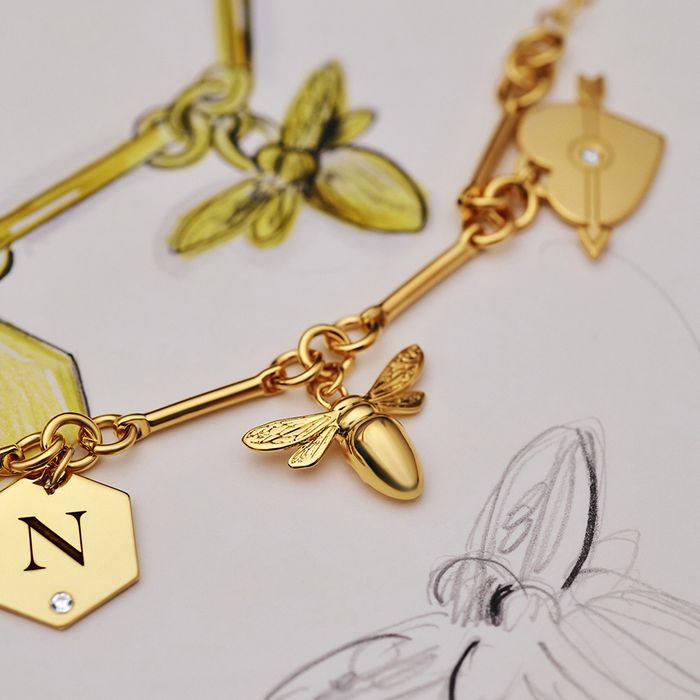 A close up of a charm bracelet with a bee on it