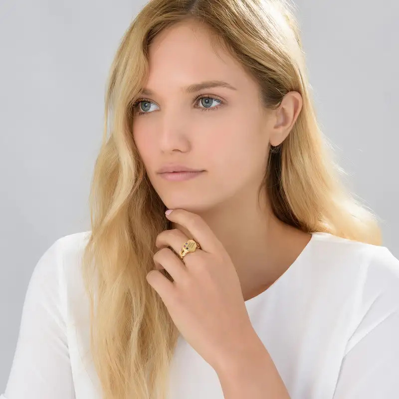 Woman wearing a heart-shaped signet ring with birthstones
