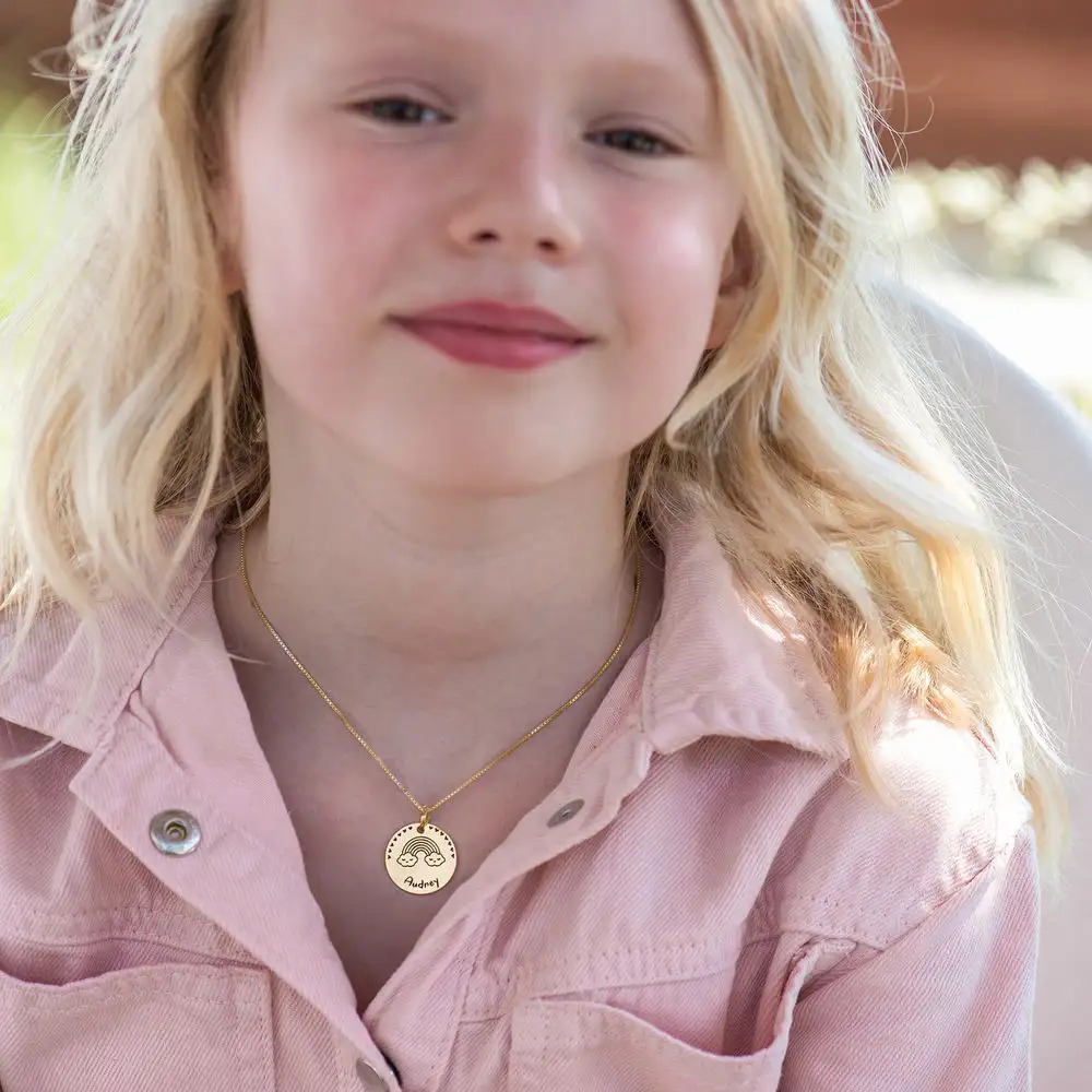 A young girl wearing a gold necklace inscribed with kid's drawing