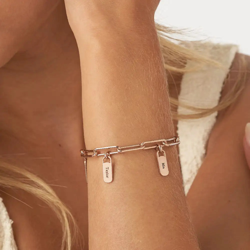 A rose gold bracelet with charms inscribed with names around a woman's wrist