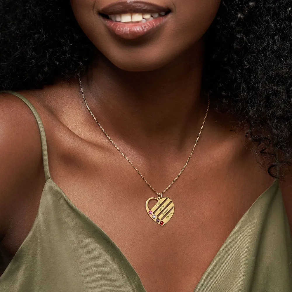 Woman wearing a gold heart-shaped necklace inscribed with names with birthstones