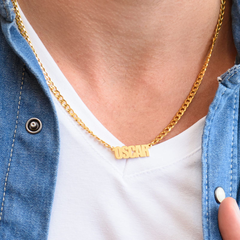 A gold thick-chain name necklace that reads "Oscar" around a man's neck