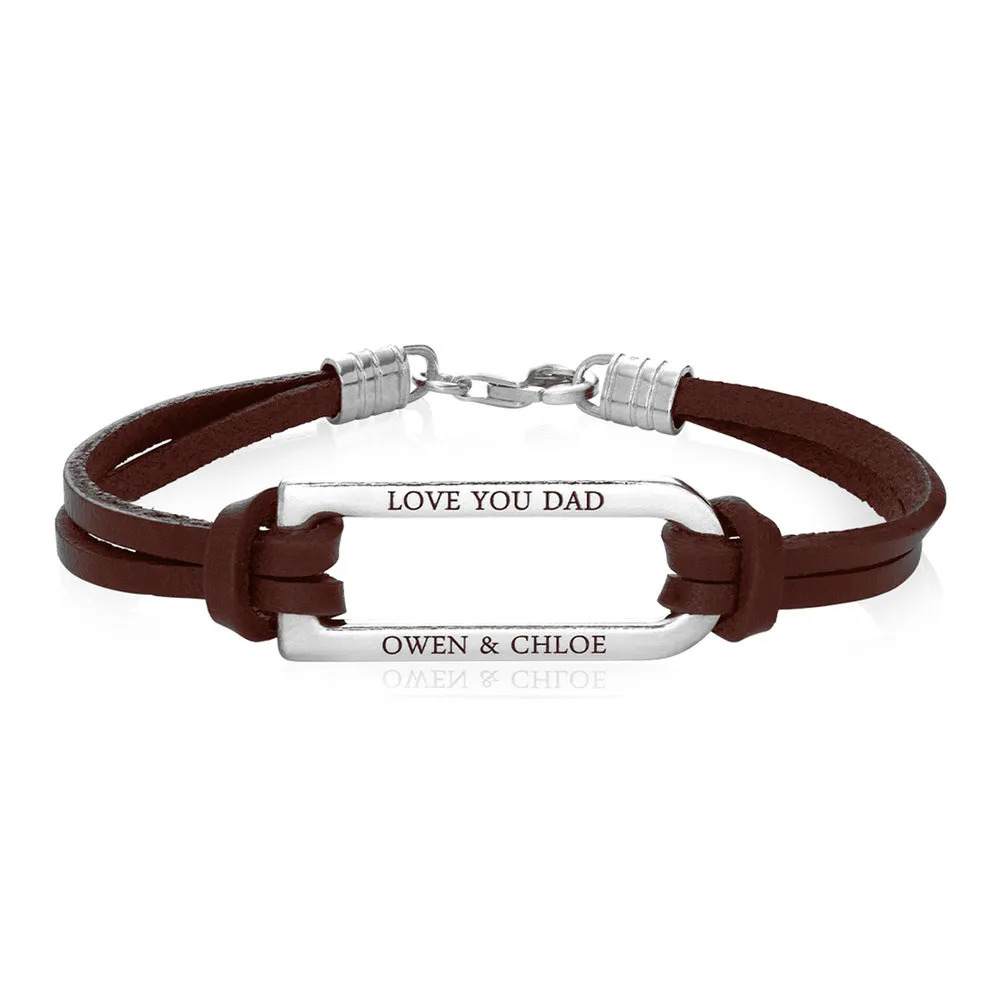 Stock image of a brown leather bracelet with an inscription on a silver bar