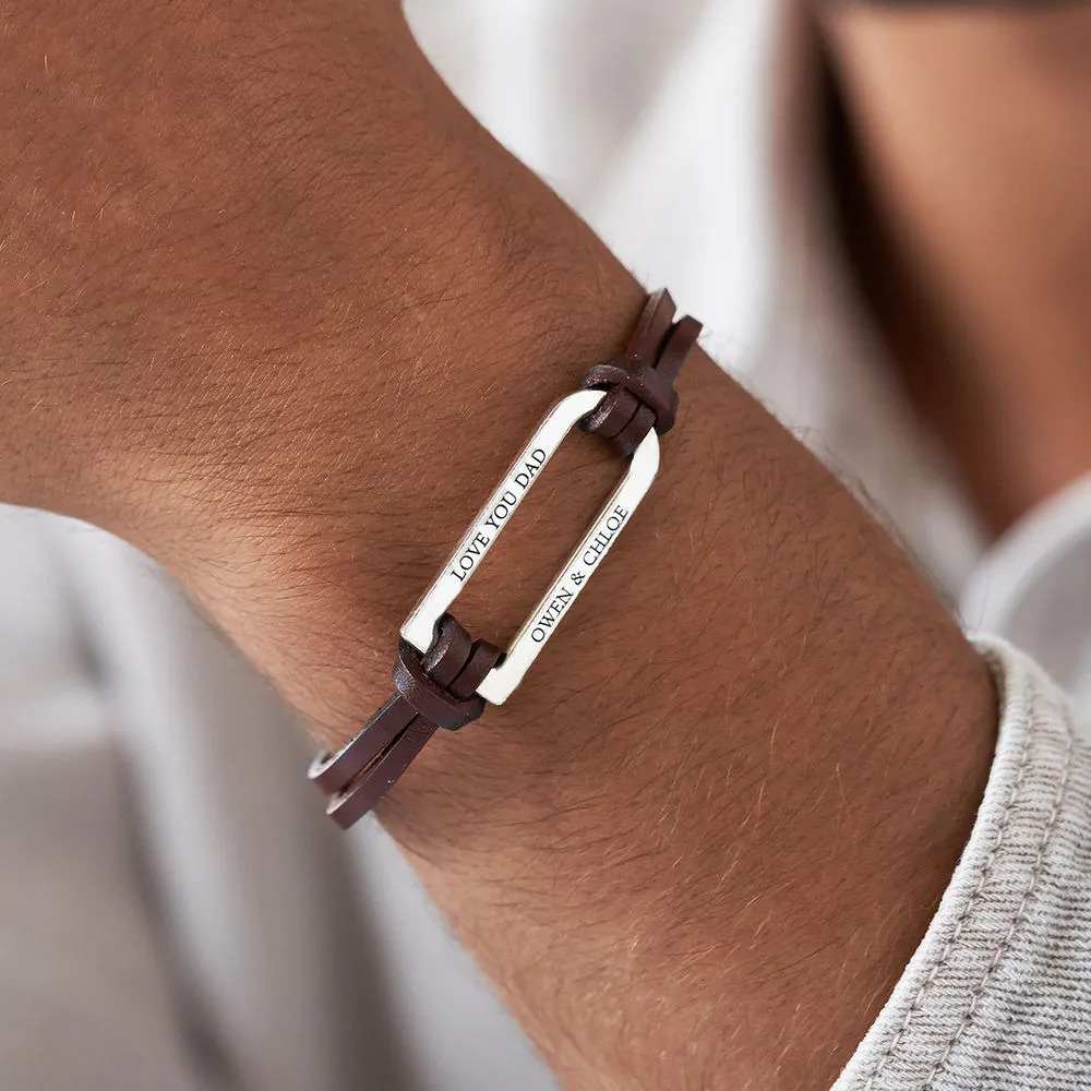 Man wearing a brown leather bracelet with an inscribed silver bar 