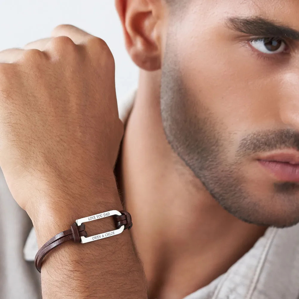 Man wearing a brown leather bracelet with an inscribed silver bar  