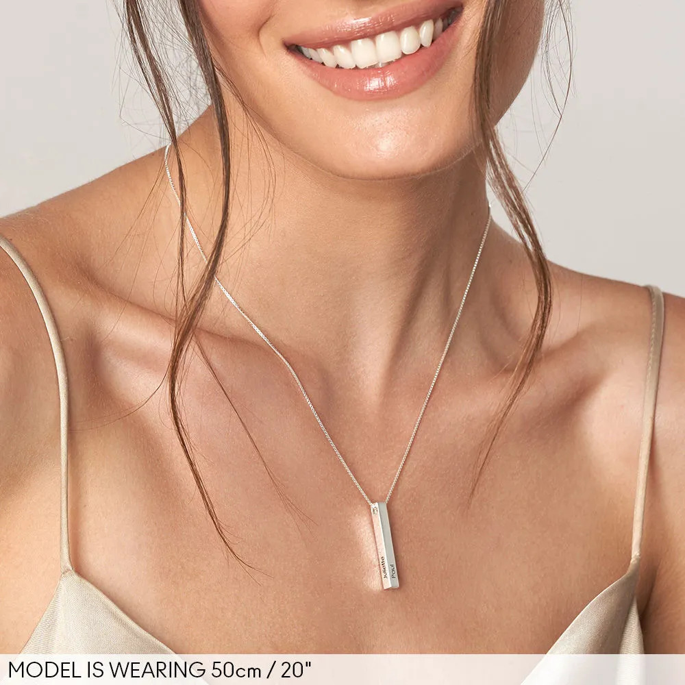 Woman smiling and wearing a silver necklace with a vertical bar pendant
