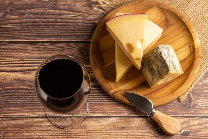 Glass of red wine paired next to a cheese board and knife with different types of cheese