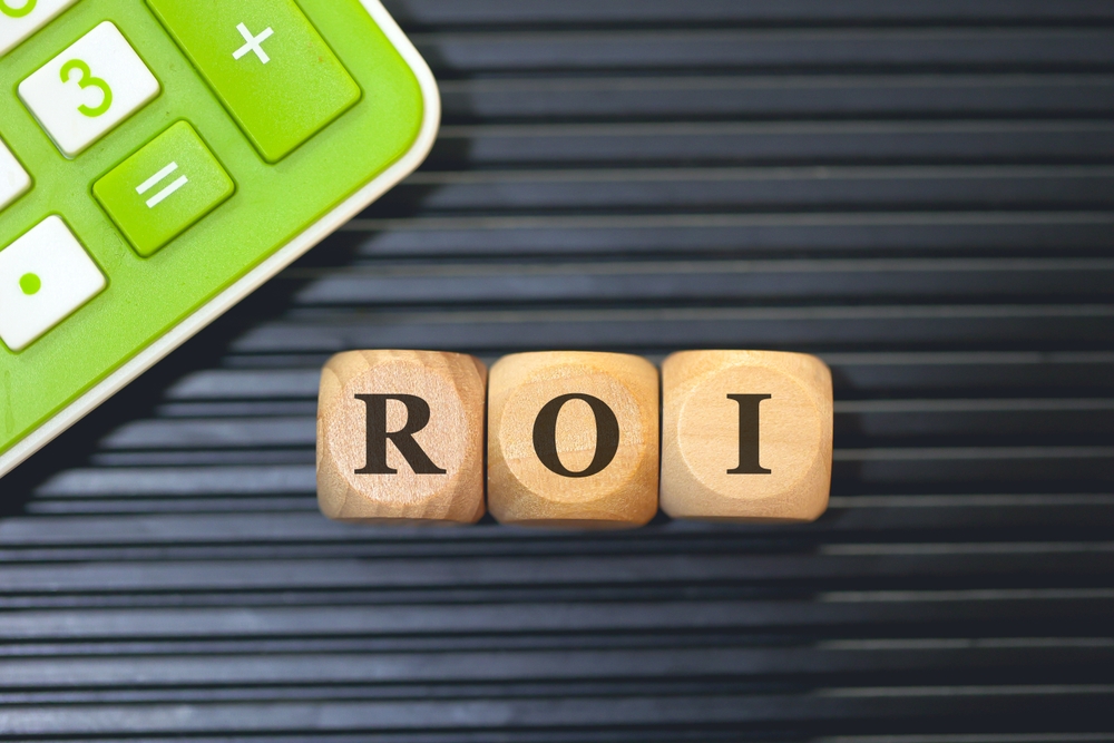 Small wooden letters spelling ROI with a green and white calculator in the corner