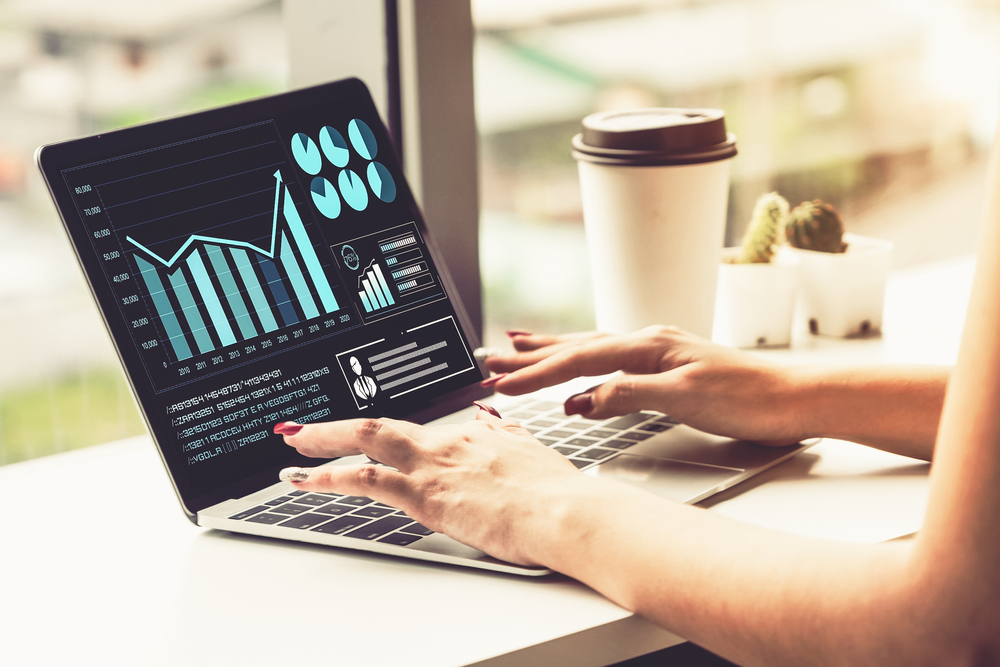 Close-up of a woman using a laptop with office real estate data visualizations on the screen