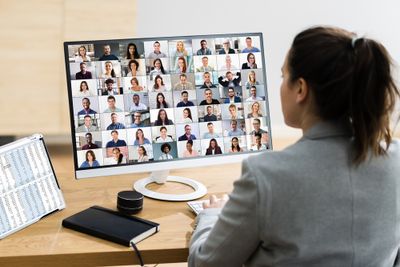 Woman in an office video conferencing with hybrid working employees of a big company