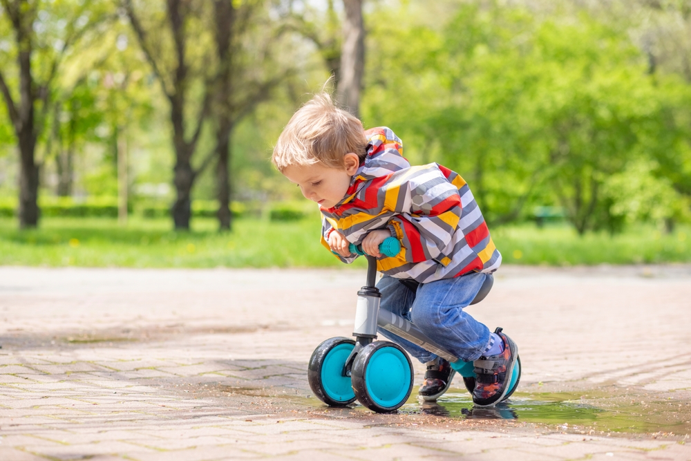 A focused toddler trying out a balance bike in a park