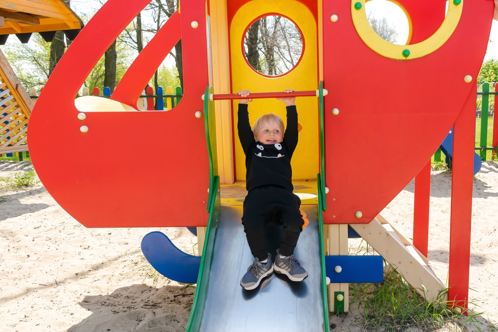 Blonde toddler playing in the playground enjoying physical activity