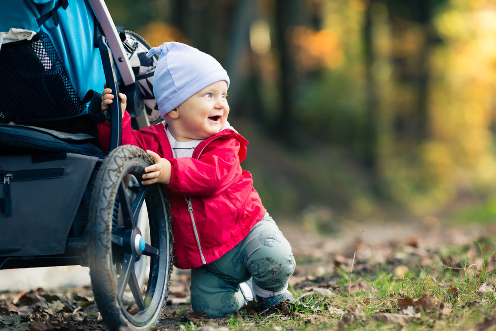 A young child playing with a stroller in the park